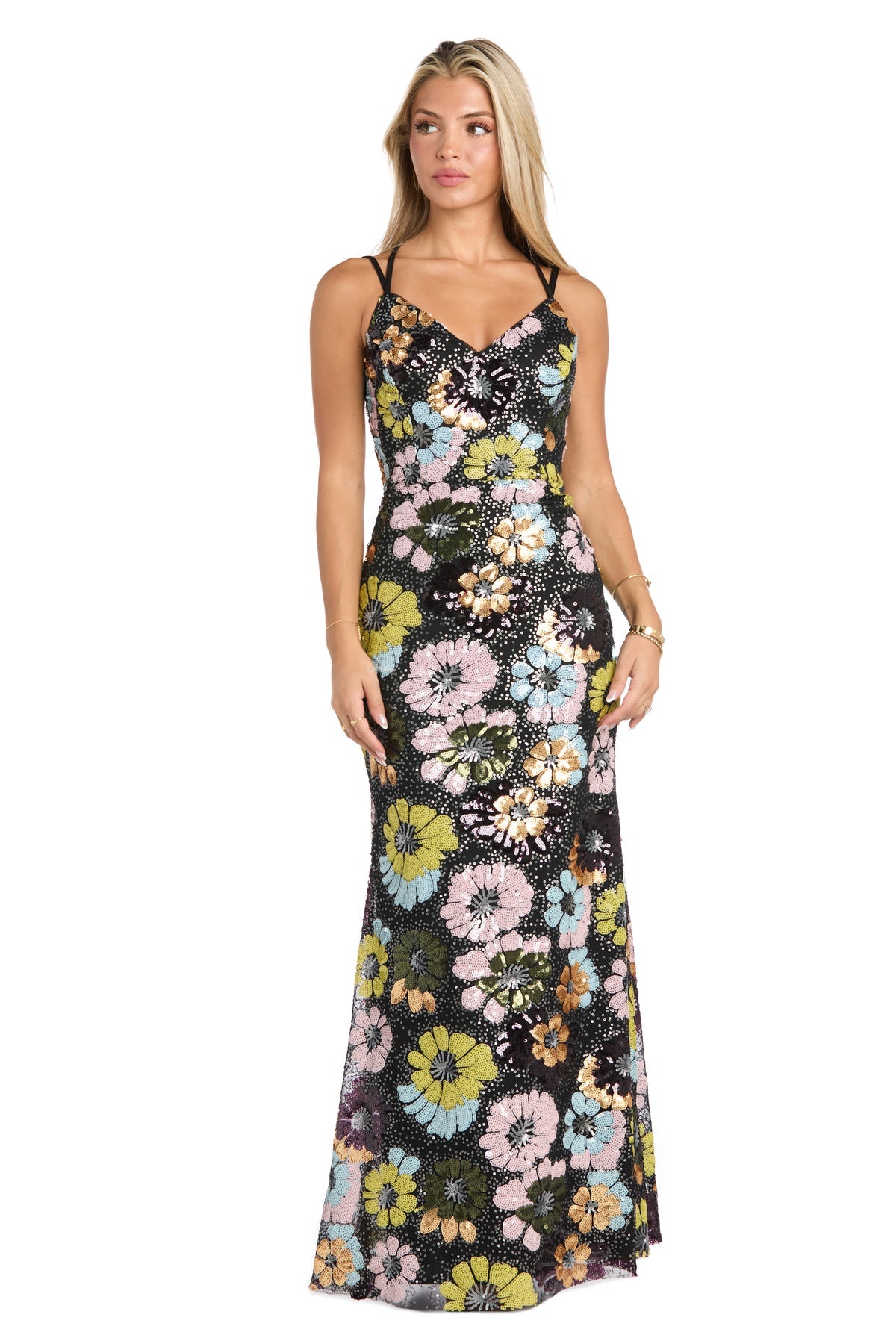 A woman models the Morgan 19051 Floral-Sequin Long Black Prom Dress, featuring colorful floral patterns, standing facing forward with her arms relaxed at her sides.